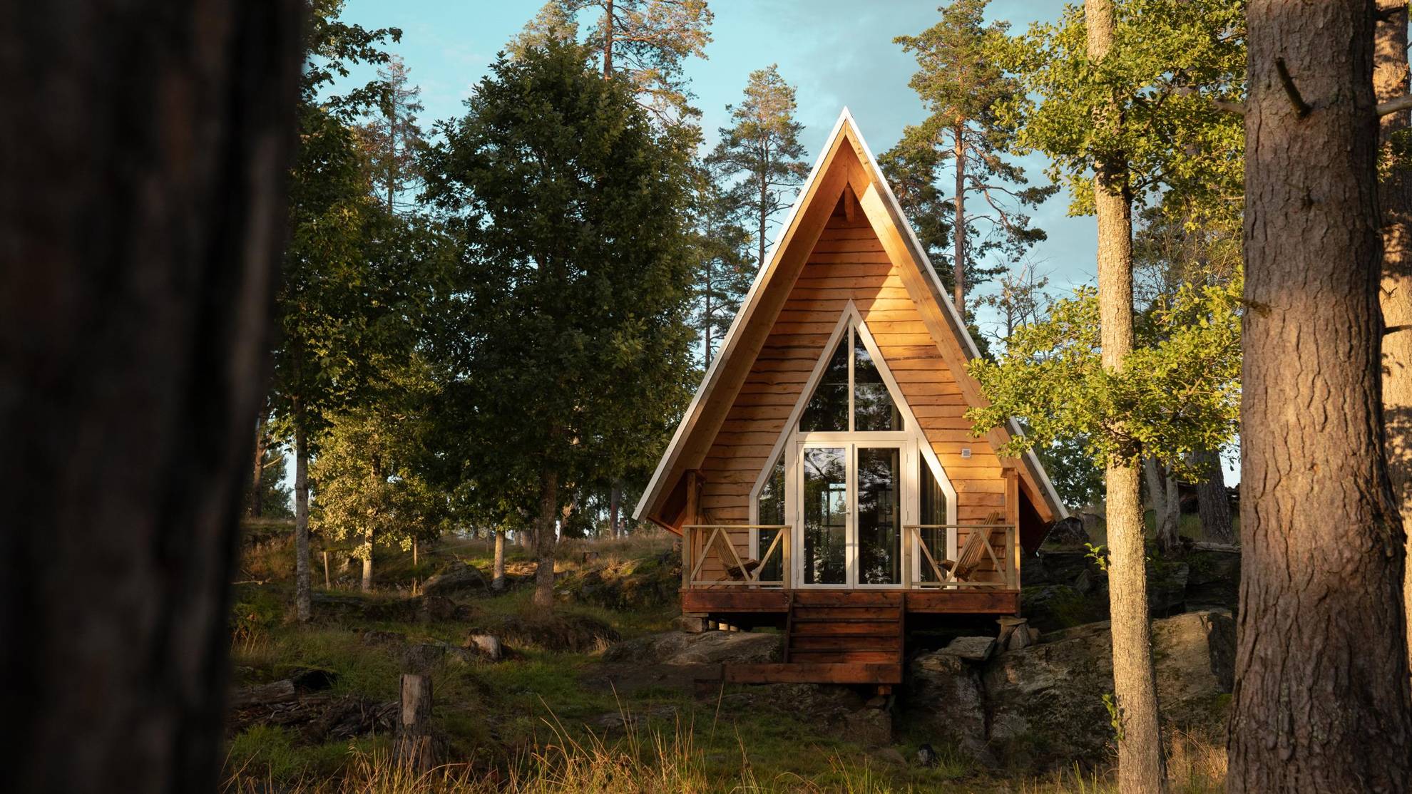 An a-frame house with glass doors located in the forest.
