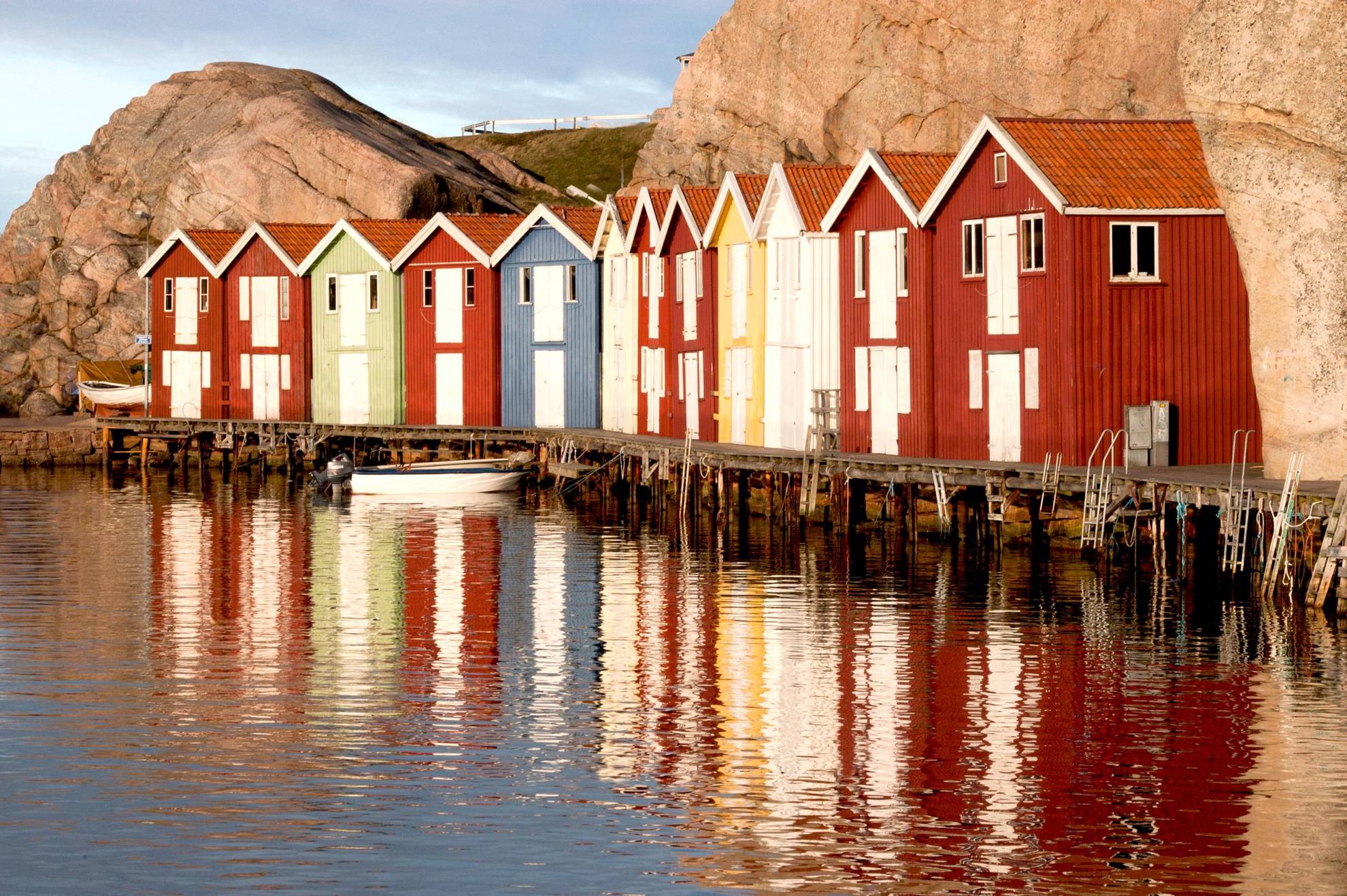 In Smögen, colourful fishing huts line up against the cliffs, their silhouettes reflected in the ocean. .