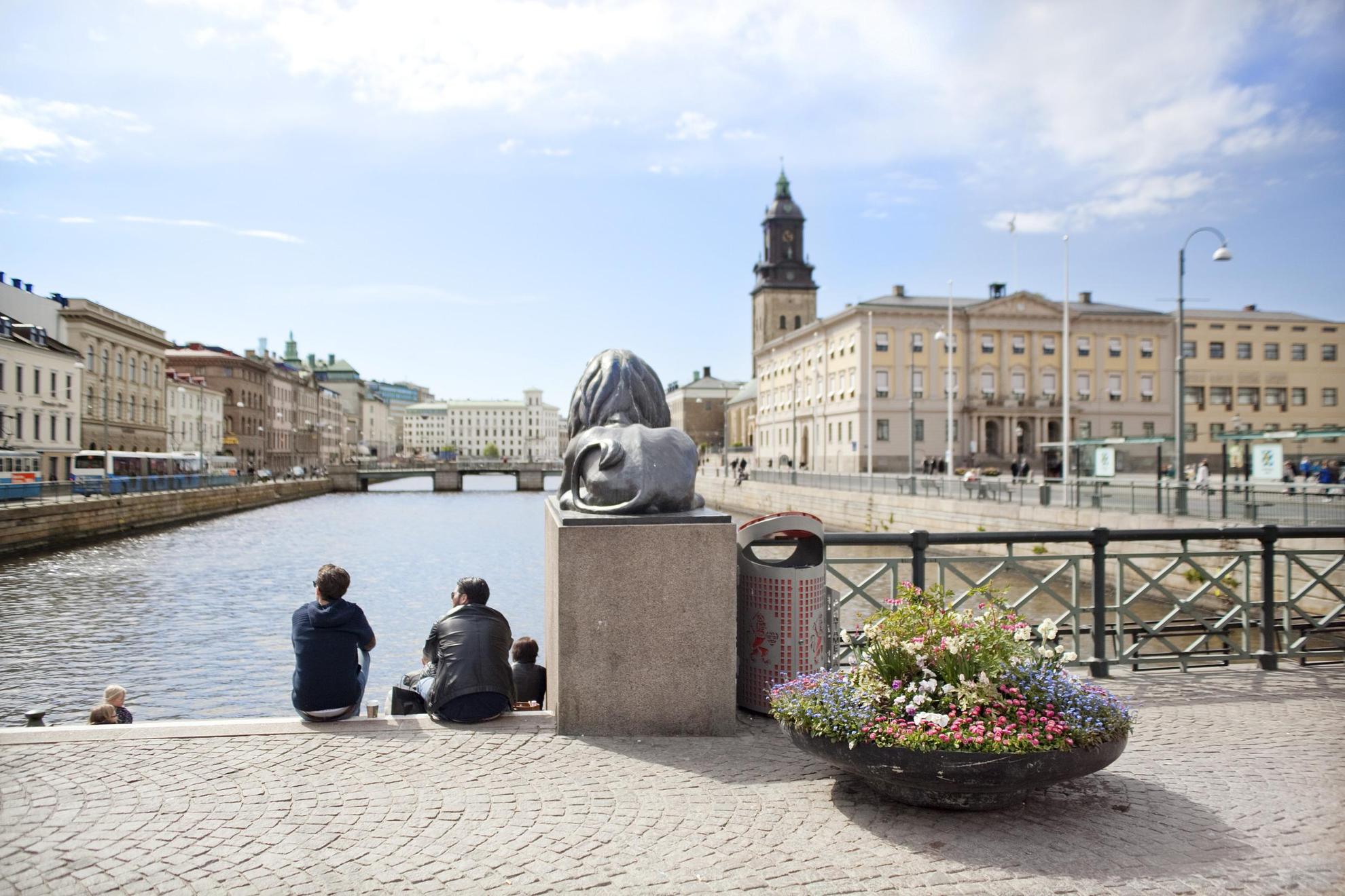 Two people sit on Lejontrappan in Brunnsparken. Gothenburg City Hall is visible in the background.