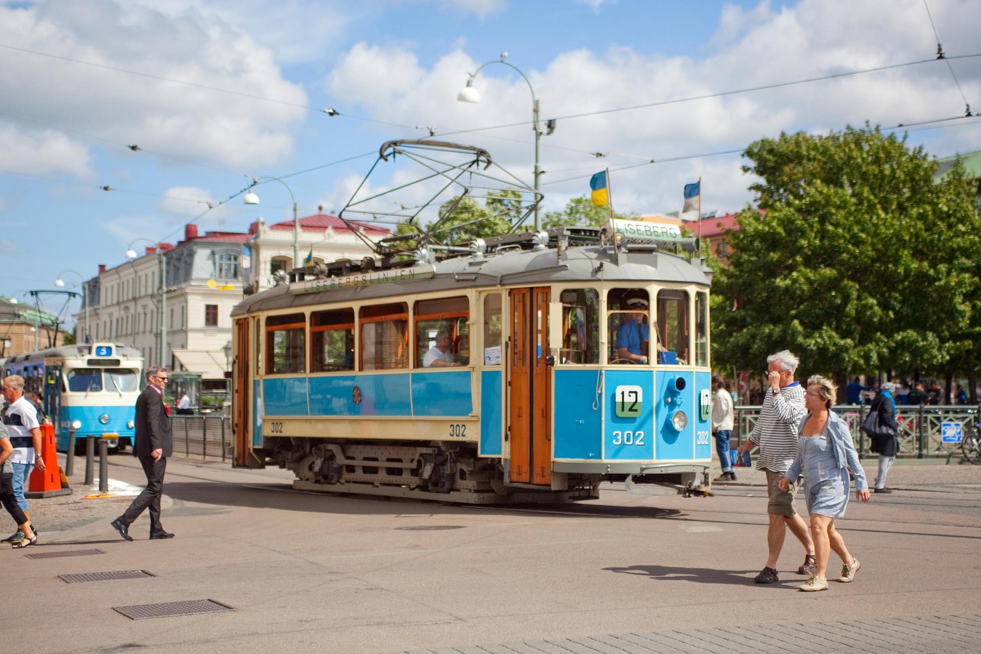 An old-fashioned tram runs on the street in the centre of Gothenburg. It is summer and daylight.