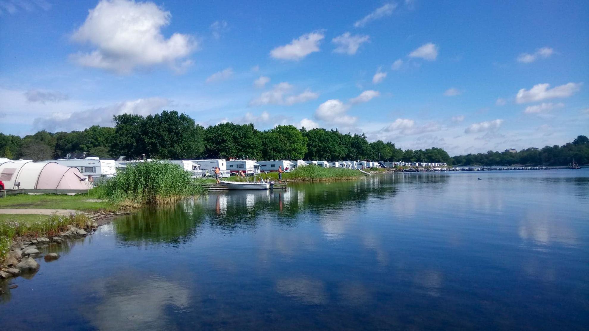 Caravans and tents are in a row next to the water at Dragsö Camping.