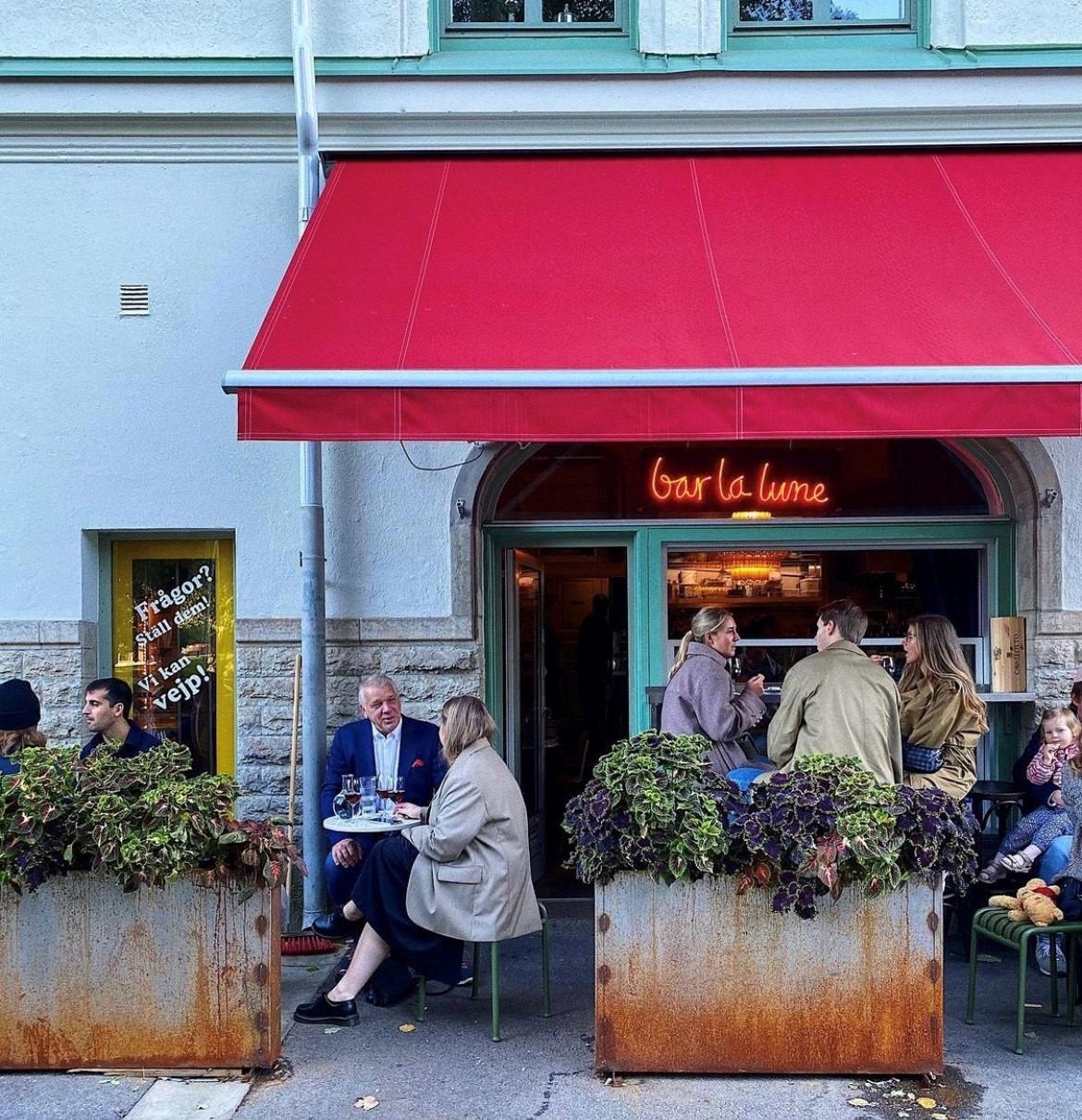 People sitting outside a restaurant enjoying food and drinks.