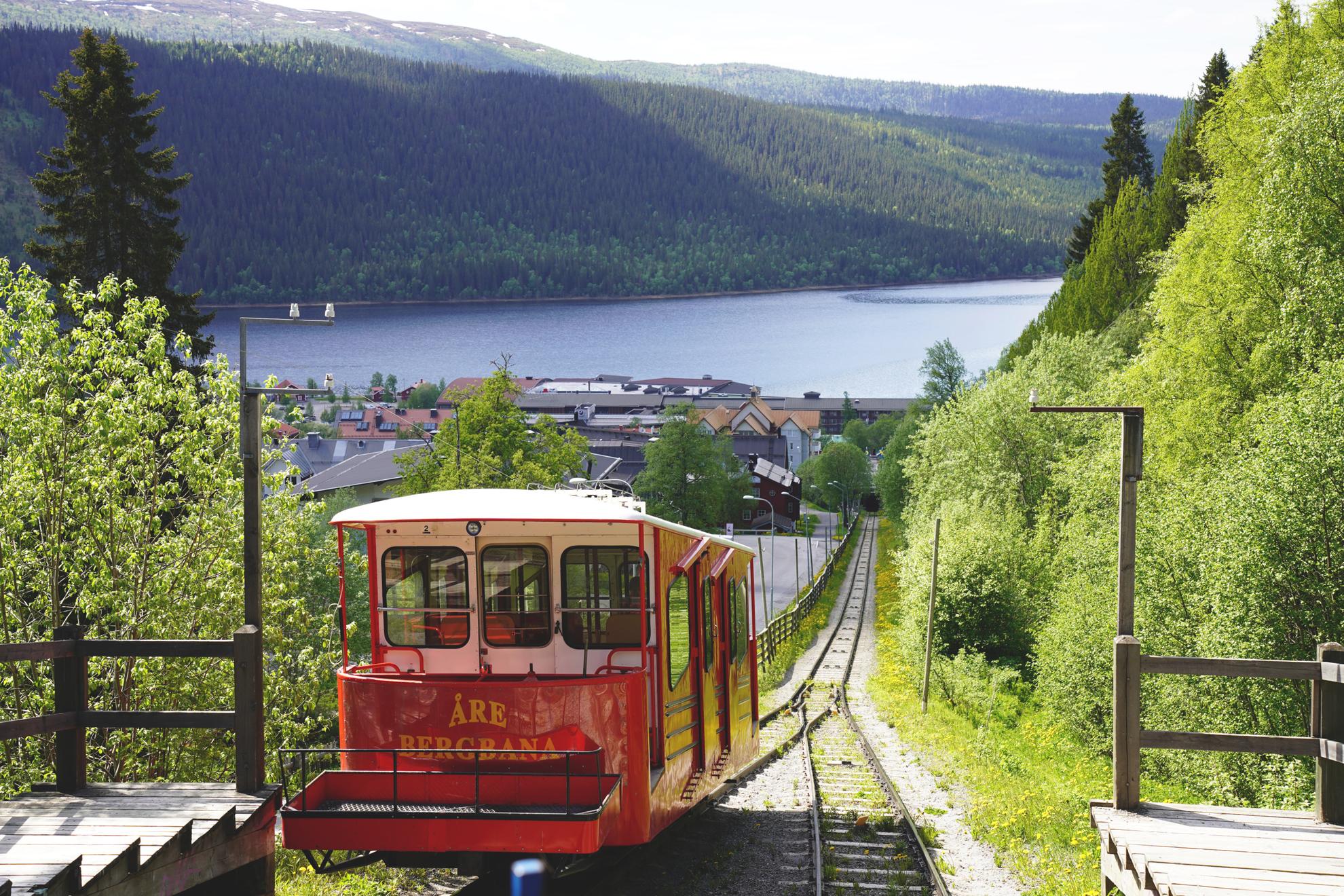 The view from on of the funicular in Åre during summer. A red cable car is on its way down.