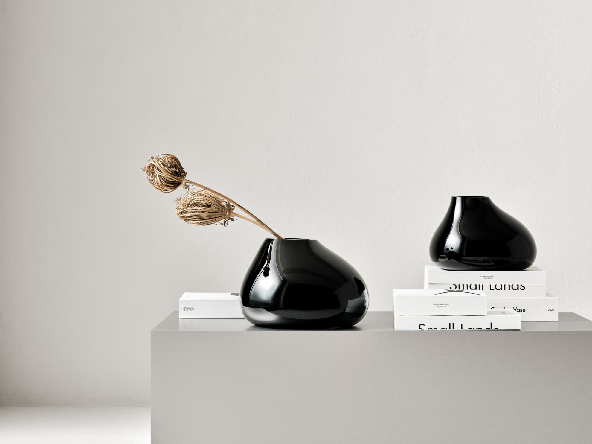 Two black vases presented on a grey box.