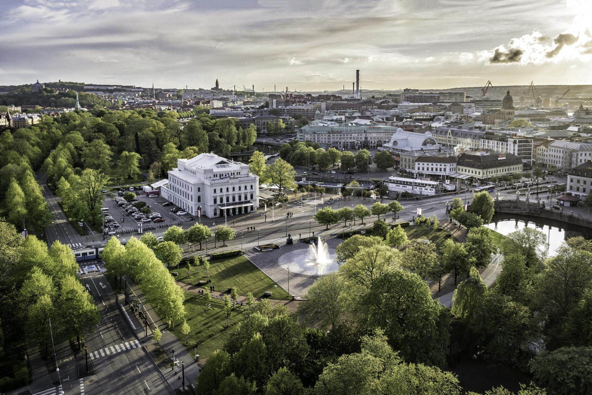 Aerial view of Gothenburg. A large white building, a fountain and lush greenery in the foreground.