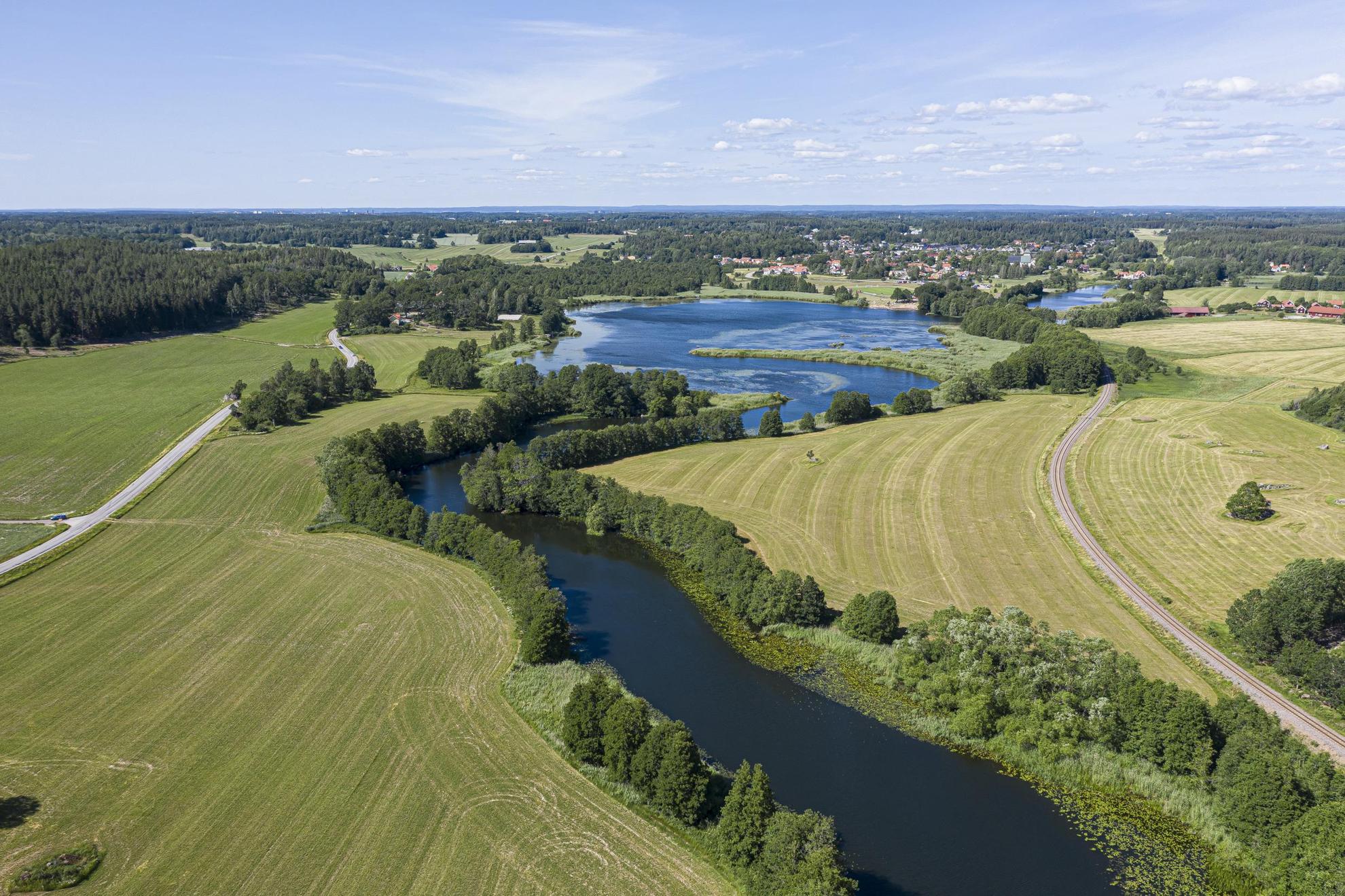 An aerial view of a river that winds between green fields and trees.