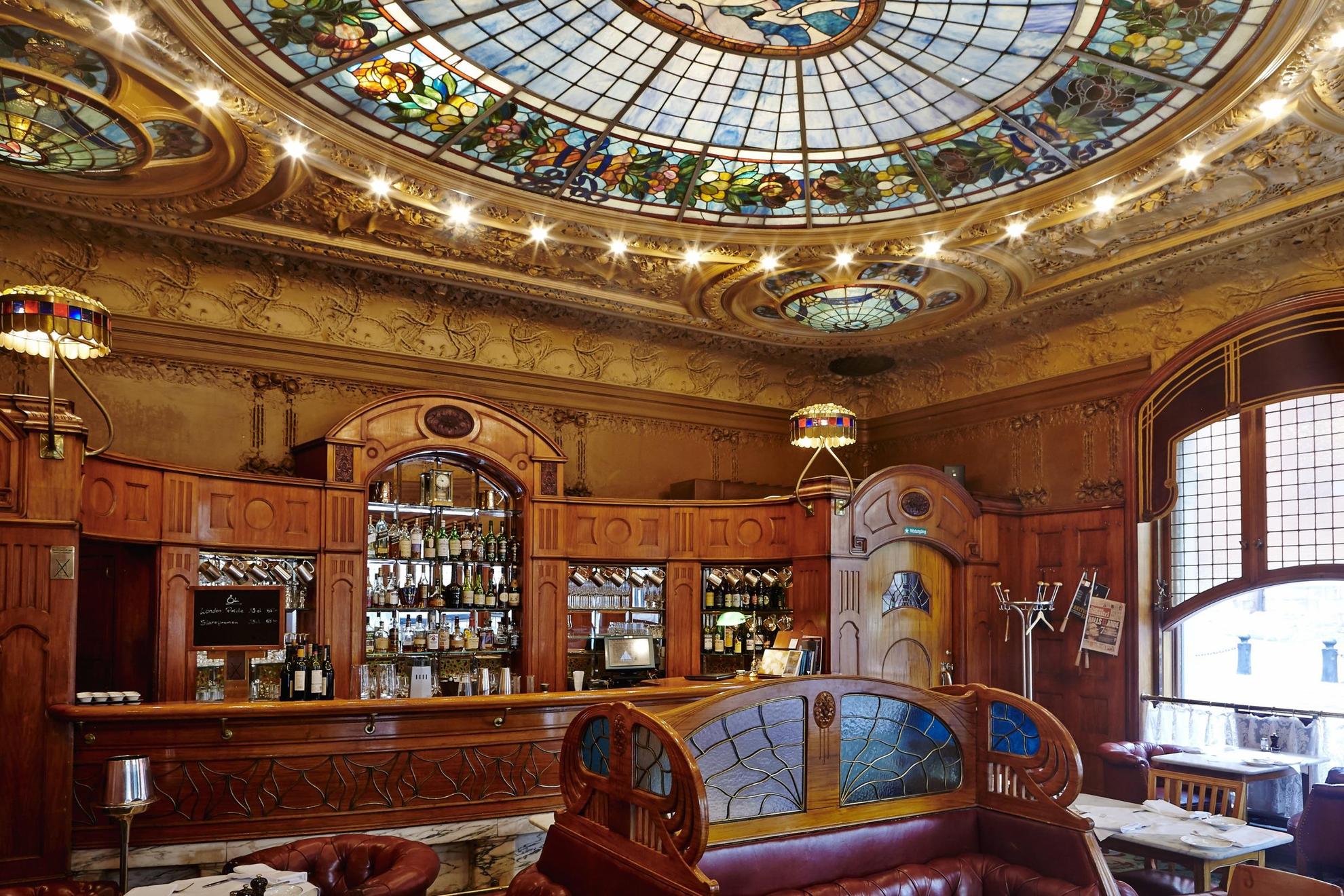 The interior of Operabaren restaurant in Stockholm, with wood ornaments and a decorative glass ceiling.