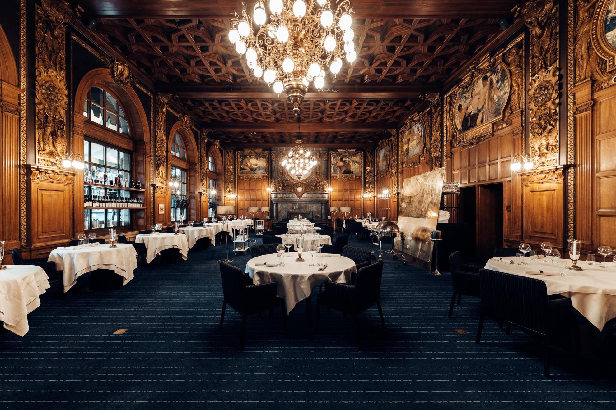 The dining room at Operakällaren with wooden walls and chandeliers.