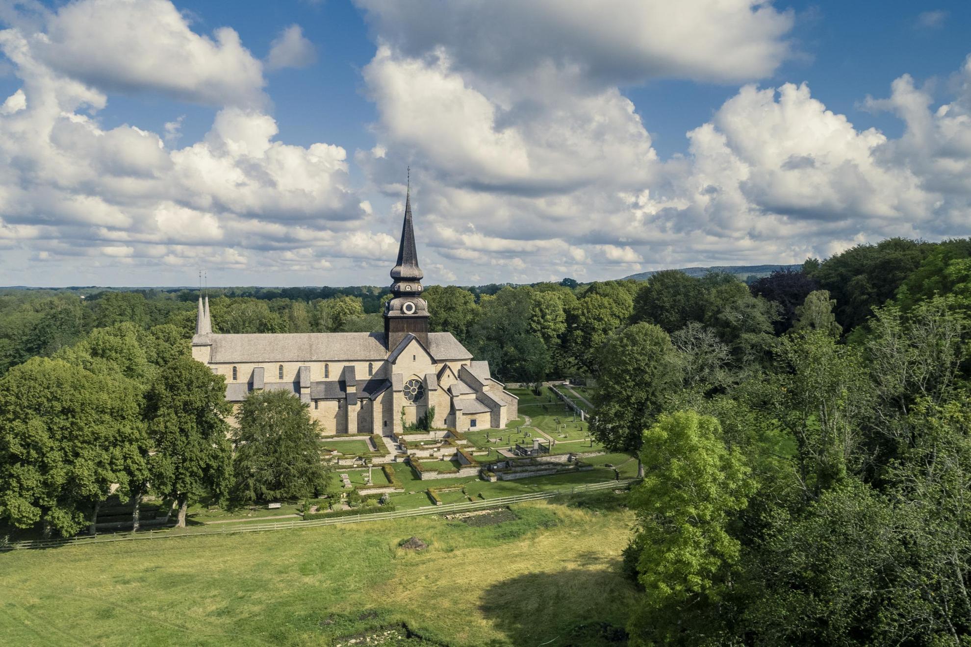 Aerial view of a medieval church, its graveyard and the surrounding fields and forests.