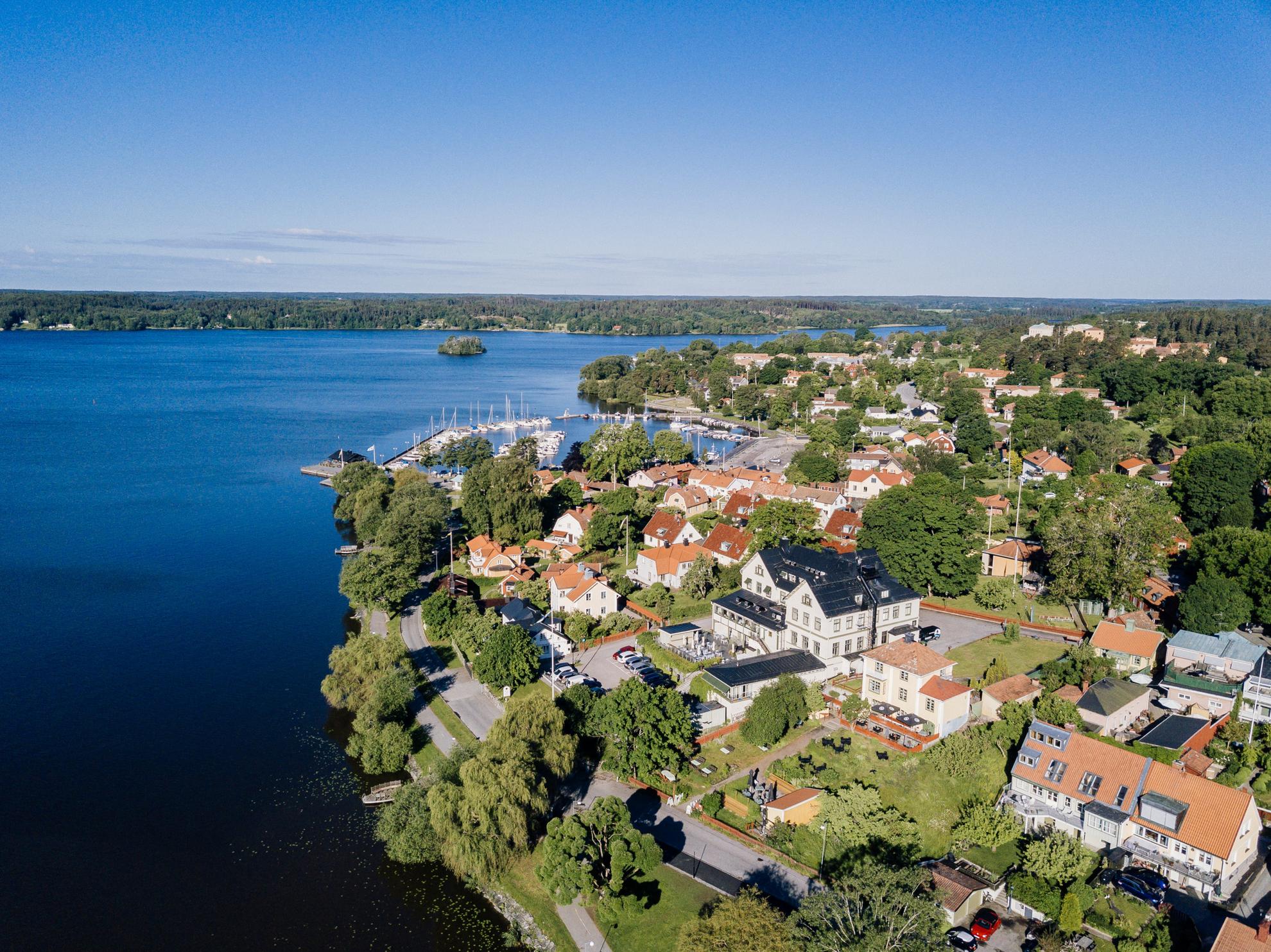 Aerial view of houses and a road next to lake Mälaren during the summer.