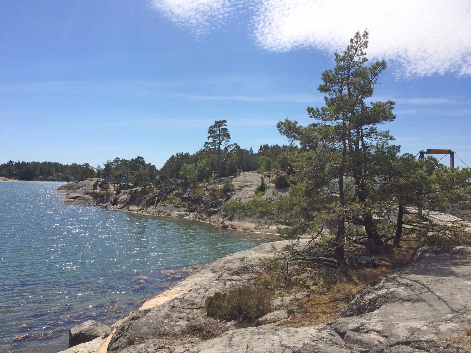 Trees grow on rocks, water on the left side. Behind the trees you hardly can recognize the small bridges that connect the rocky islands.