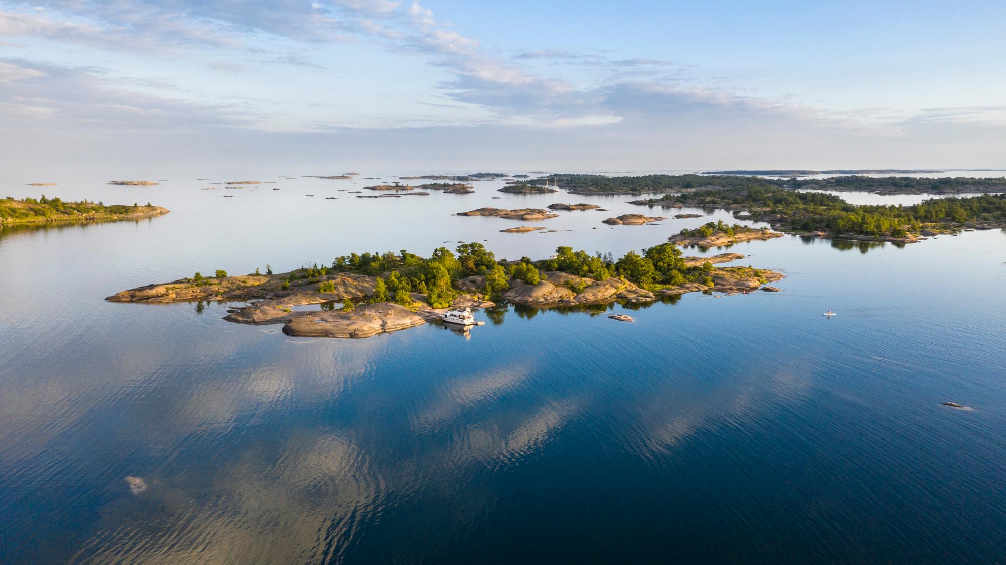 Aerial image of a boat next to an island in the Stockholm archipelago during a summer day.