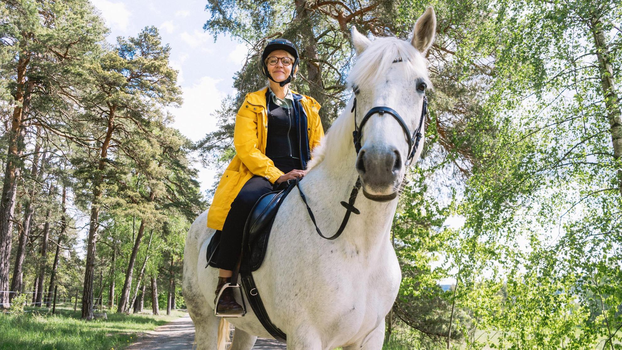 A woman is sitting on a white horse.