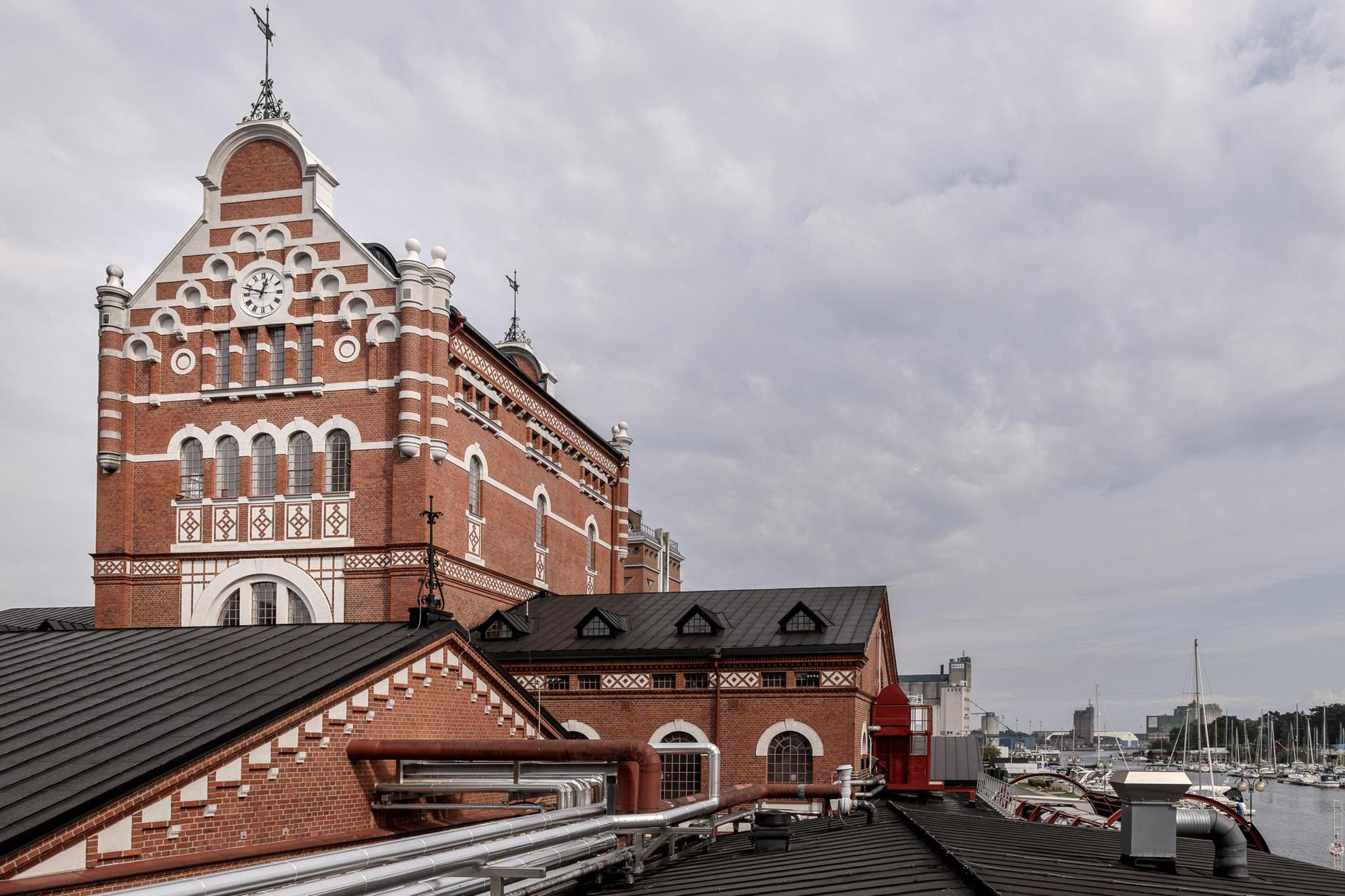 a large red brick building with white decorative features, by a harbour.