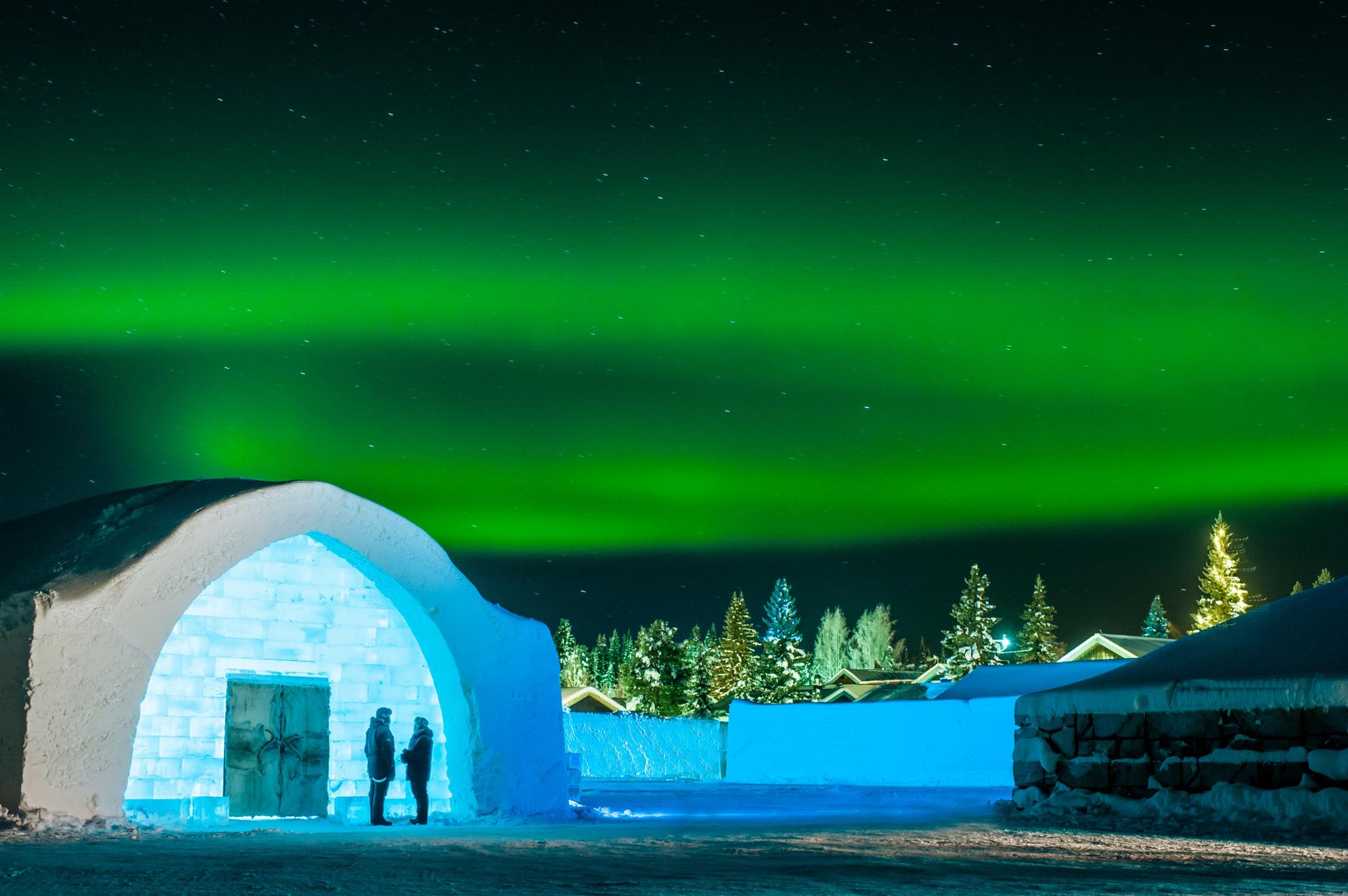 Green northern lights shine above the entrance to the Icehotel.