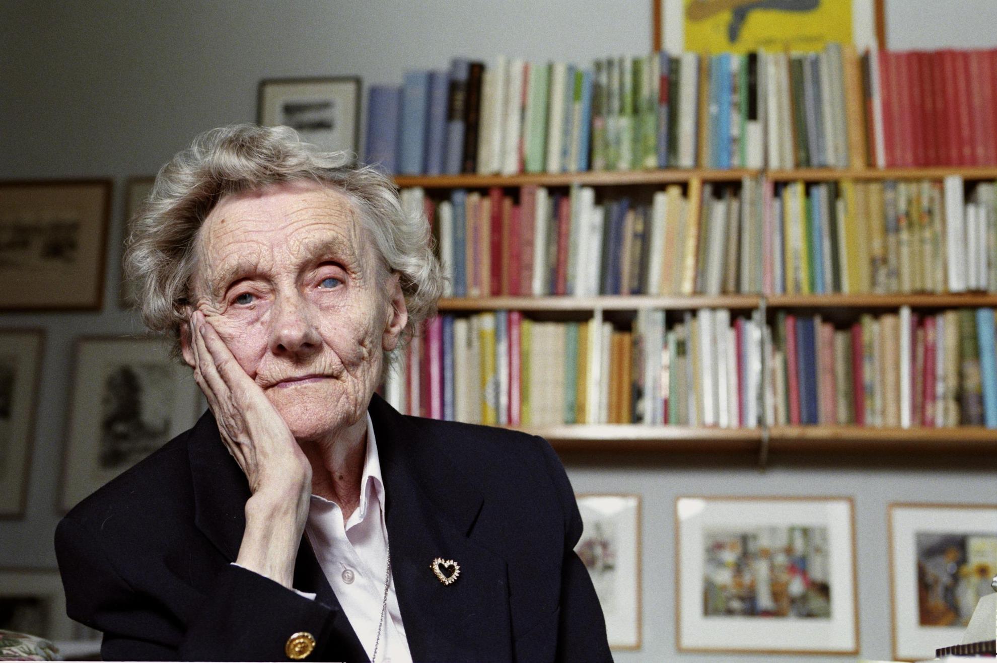 Portrait of author Astrid Lindgren in front of a book shelf.